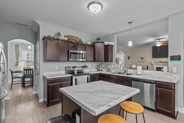 kitchen with a breakfast bar, pendant lighting, sink, kitchen peninsula, and stainless steel appliances