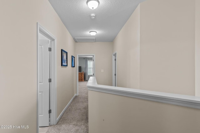 corridor featuring light carpet and a textured ceiling