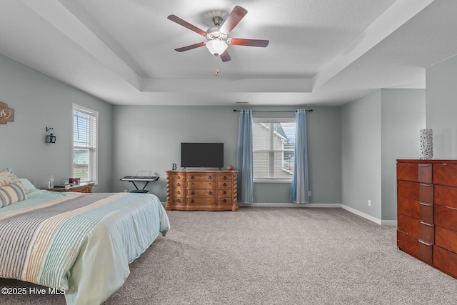 bedroom with multiple windows, carpet, and a tray ceiling