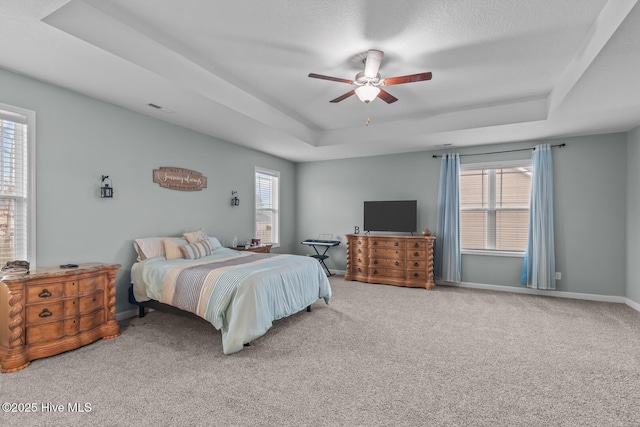 bedroom featuring multiple windows, carpet floors, ceiling fan, and a tray ceiling