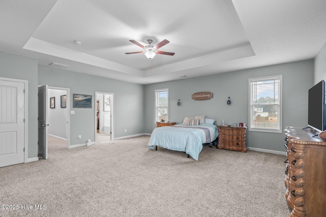 bedroom with multiple windows, light carpet, and a raised ceiling