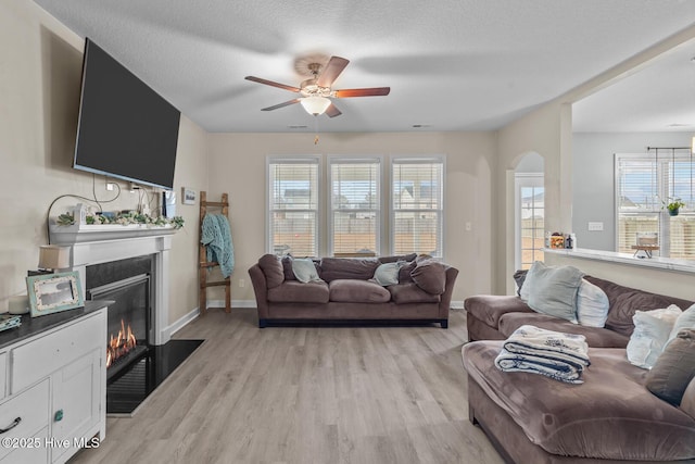 living room with ceiling fan, light hardwood / wood-style flooring, and a textured ceiling