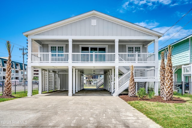 301 43rd Ave N, North Myrtle Beach, SC 29582 - raised beach house featuring a carport, concrete driveway, covered porch, fence, and stairway