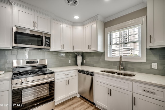 301 43rd Ave N, North Myrtle Beach, SC 29582 - kitchen with white cabinetry, crown molding, a sink, appliances with stainless steel finishes, and visible vents