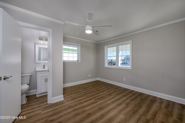 unfurnished bedroom with connected bathroom, dark wood-type flooring, ornamental molding, and ceiling fan