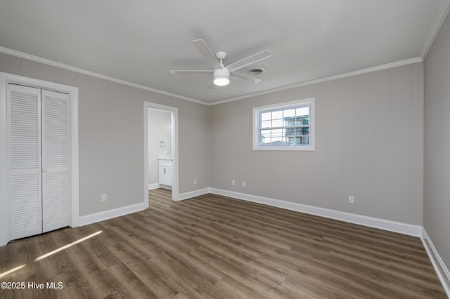 unfurnished bedroom with crown molding, dark wood-type flooring, a closet, and ceiling fan