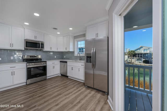 kitchen featuring white cabinetry, stainless steel appliances, sink, and light wood-type flooring