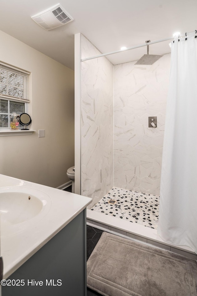 full bathroom featuring toilet, a stall shower, vanity, and visible vents