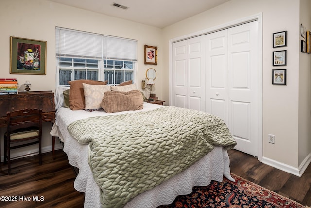 bedroom with dark wood-style floors, a closet, visible vents, and baseboards