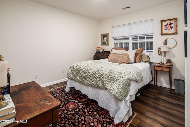 bedroom with dark wood-style flooring, visible vents, and baseboards