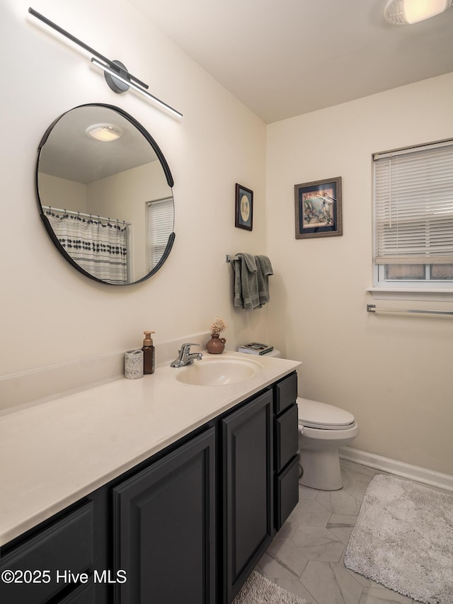 bathroom with toilet, marble finish floor, baseboards, and vanity