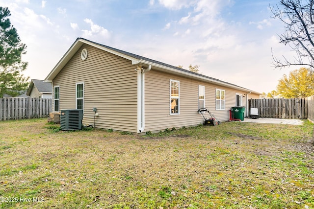 view of property exterior featuring cooling unit, a fenced backyard, and a lawn