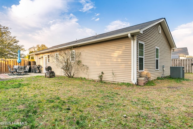 rear view of property with central AC, fence, a patio, and a lawn