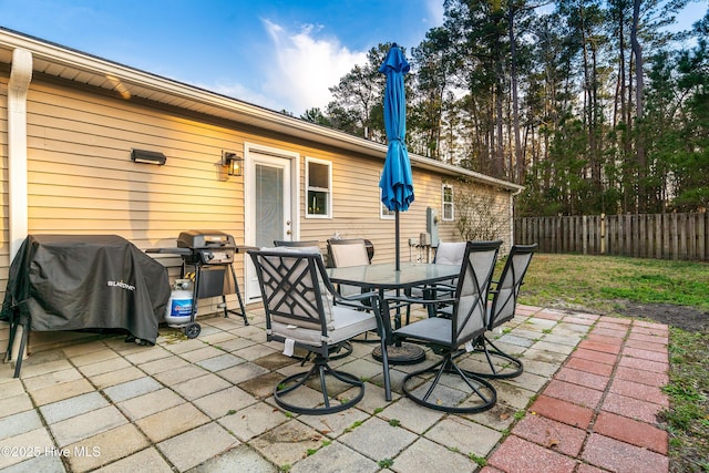 view of patio featuring grilling area, fence, and outdoor dining area