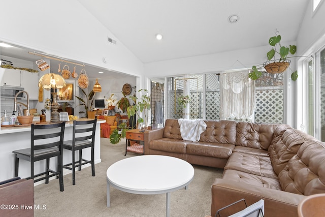 living room with sink, light colored carpet, and high vaulted ceiling