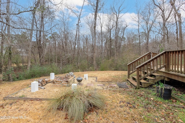 view of yard with a wooden deck and a fire pit