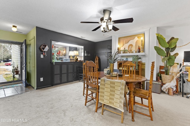 carpeted dining area featuring ceiling fan and a textured ceiling