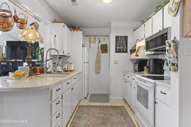 kitchen with white cabinetry, sink, light tile patterned floors, and white appliances