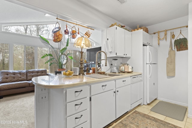 kitchen with white cabinetry, sink, light tile patterned flooring, and white appliances