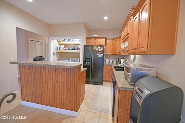 kitchen with sink, light tile patterned flooring, and black fridge