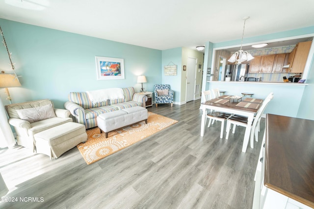 living area with an inviting chandelier, light wood-style flooring, and baseboards