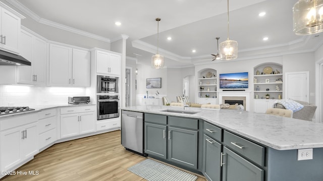 kitchen with open floor plan, a fireplace, white cabinets, stainless steel appliances, and a kitchen island with sink