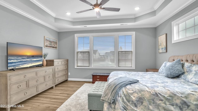 bedroom featuring a tray ceiling, multiple windows, and light wood finished floors