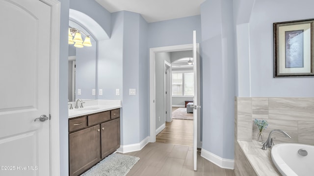 bathroom with a bath, vanity, and baseboards