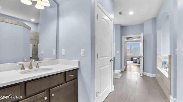 full bath featuring vanity, visible vents, baseboards, and a tub