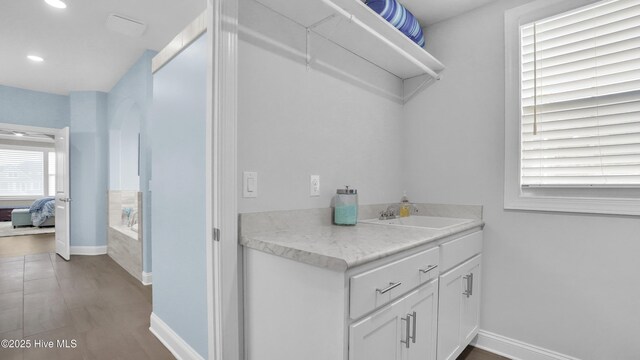 interior space with vanity, a garden tub, baseboards, and ensuite bath