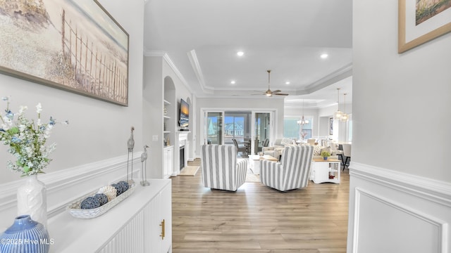 living room with ornamental molding, recessed lighting, light wood-style floors, wainscoting, and a fireplace