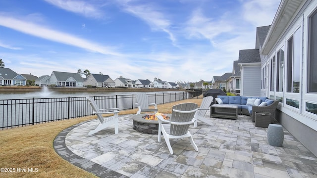 view of patio / terrace featuring a residential view, an outdoor living space with a fire pit, fence, and a water view