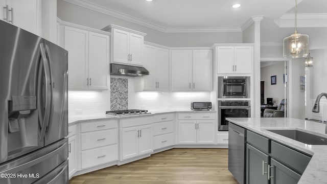 kitchen featuring under cabinet range hood, ornamental molding, appliances with stainless steel finishes, and a sink