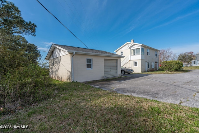 rear view of property featuring a garage, a yard, and an outdoor structure