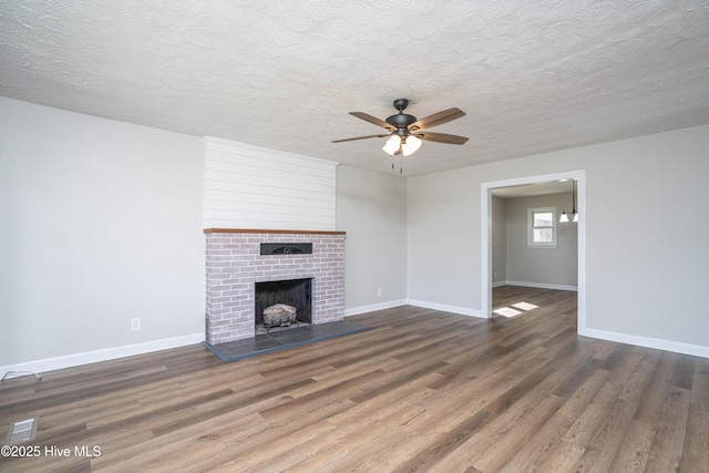 unfurnished living room with ceiling fan, dark hardwood / wood-style floors, a textured ceiling, and a fireplace