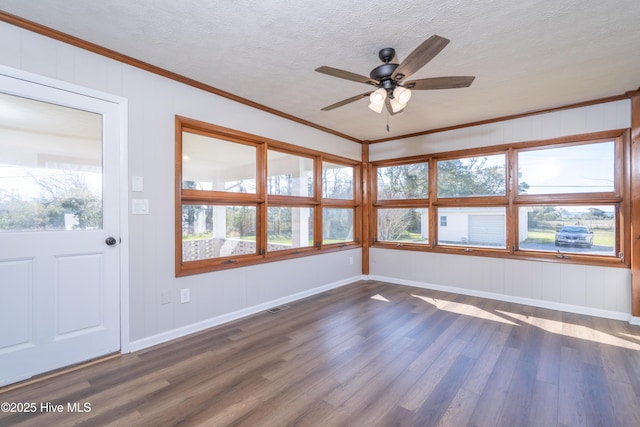 interior space featuring a wealth of natural light, dark wood-type flooring, ornamental molding, and a textured ceiling