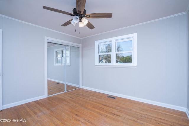 unfurnished bedroom featuring ornamental molding, ceiling fan, light hardwood / wood-style floors, and a closet