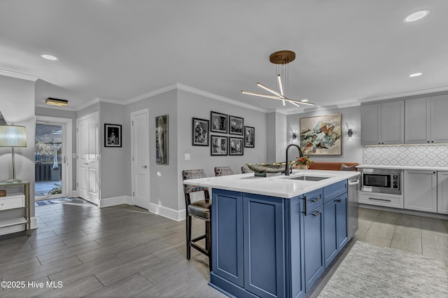 kitchen featuring light countertops, decorative backsplash, appliances with stainless steel finishes, a sink, and blue cabinets