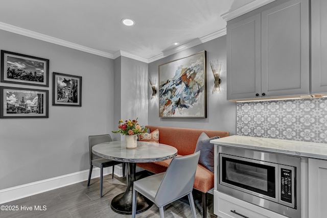 dining room with baseboards, breakfast area, wood finished floors, and ornamental molding