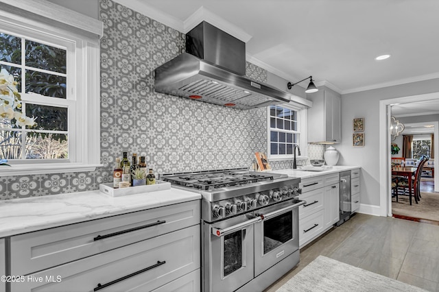 kitchen featuring tasteful backsplash, range with two ovens, wall chimney exhaust hood, crown molding, and a sink