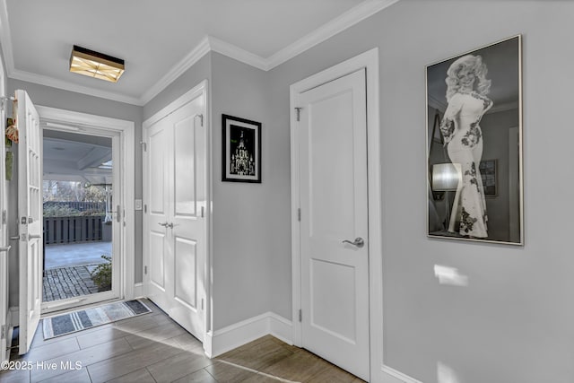 entryway with baseboards, ornamental molding, and wood finish floors