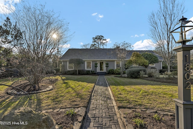 ranch-style house featuring a front lawn and stucco siding