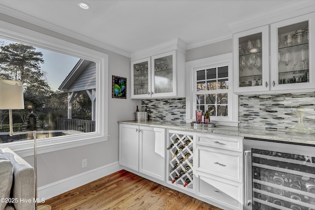 bar with wine cooler, crown molding, a bar, and wood finished floors