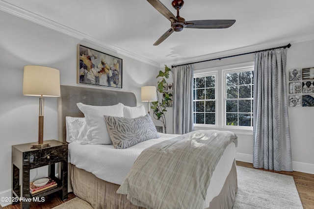 bedroom featuring ornamental molding, a ceiling fan, baseboards, and wood finished floors