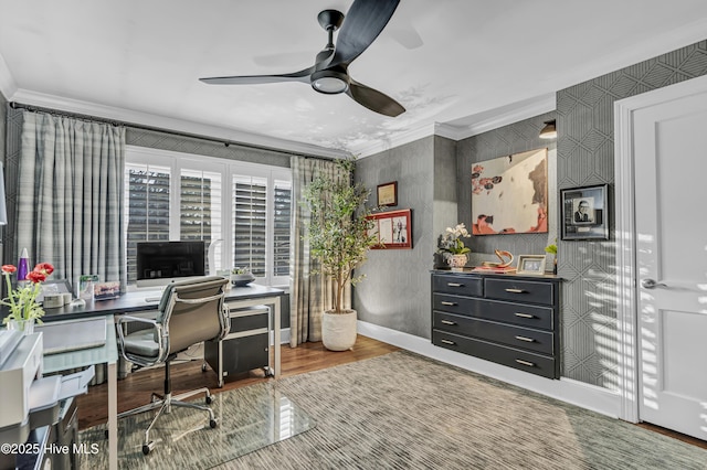 home office with crown molding, a ceiling fan, wood finished floors, baseboards, and wallpapered walls