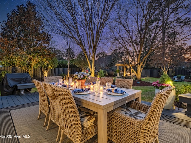 wooden deck with outdoor dining space, a patio area, and a fenced backyard