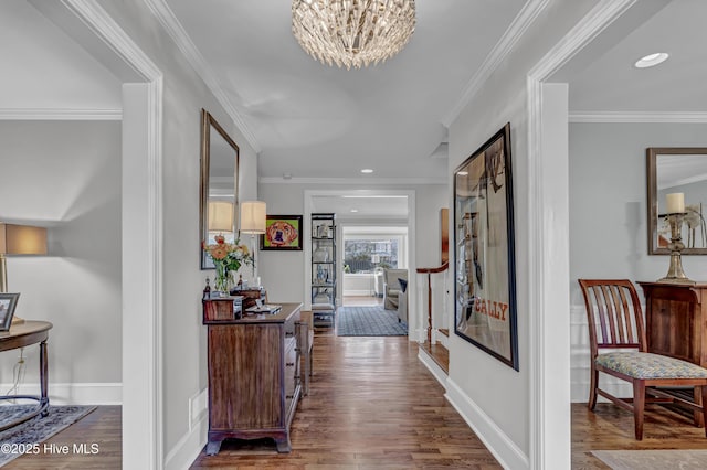 hall with ornamental molding, an inviting chandelier, baseboards, and wood finished floors