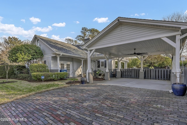 exterior space featuring decorative driveway, fence, and a ceiling fan