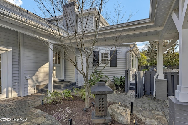 view of side of home with a chimney and fence