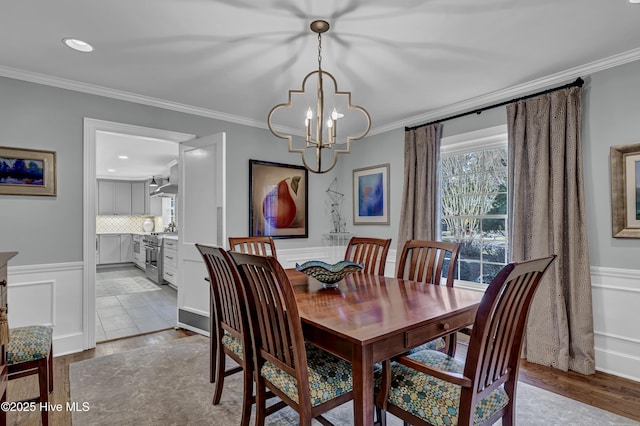 dining area with ornamental molding, wainscoting, and an inviting chandelier